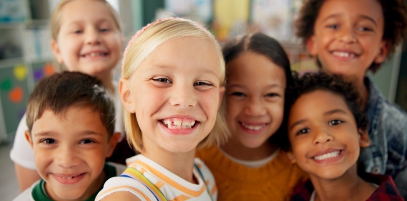 A diverse group of young children smiling at the camera.]