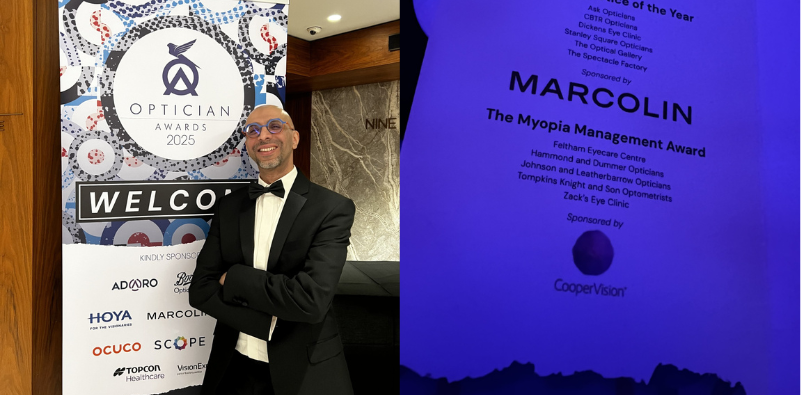 Mohamed Kasmani in a tuxedo stood in front of The Optician Awards 2025 banner on the left of the image, and on the right a photo of the list of finalists for The Myopia Management Award
