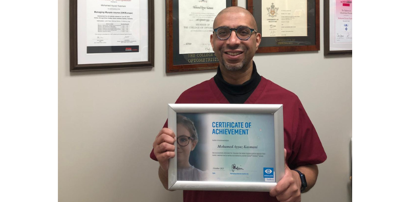 Mohamed Kasmani at Feltham Eyecare Centre holding a Certificate of Achievement for Essilor Stellest lenses.]