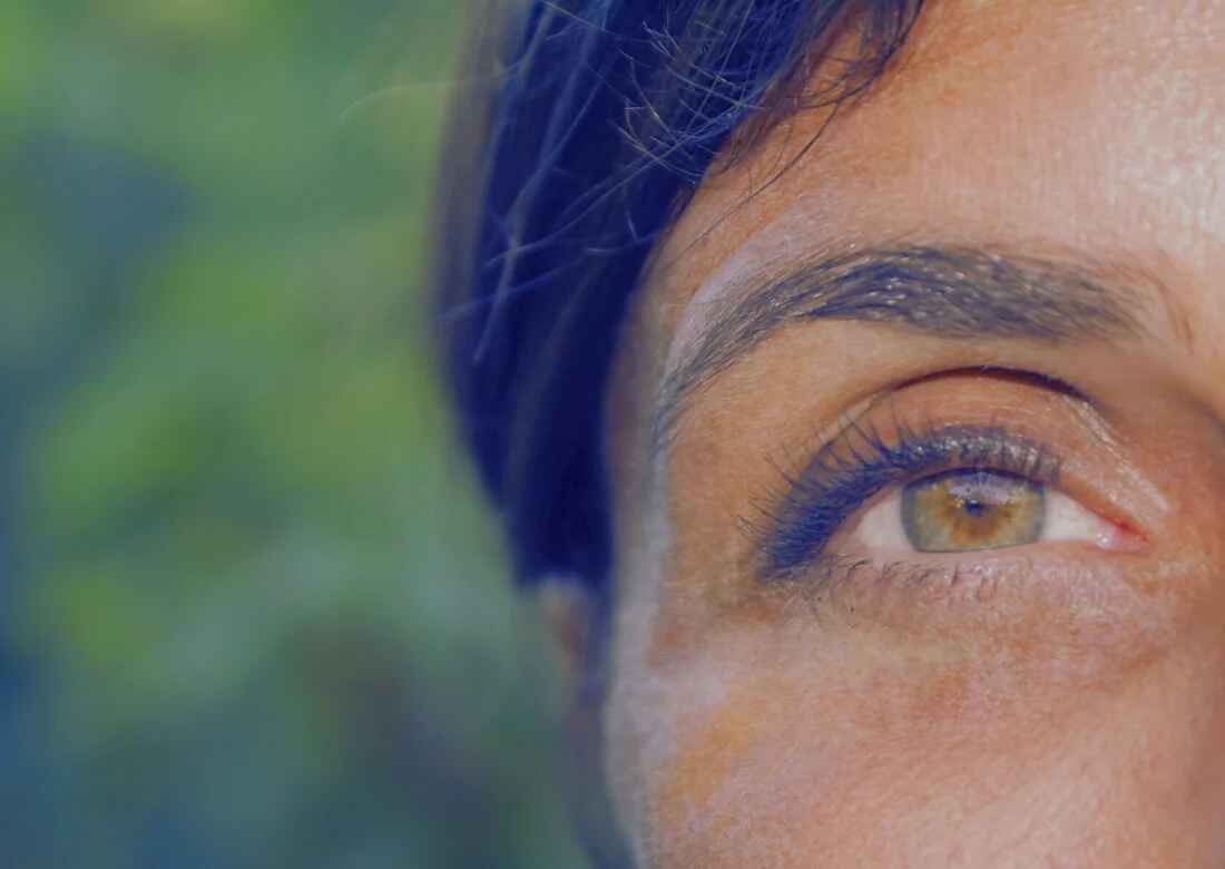 close up of woman showing side of her face and a single eye. Eyes are green.